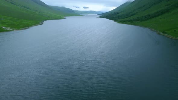 Pan up of Glen Etive water in between mountainous peaks covered by clouds