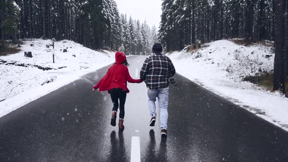 Happy Winter Couple Running Though the Winter Forest