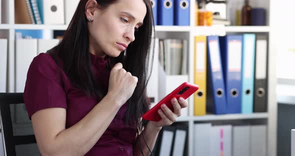 Sad Young Woman Looks at Smartphone Screen