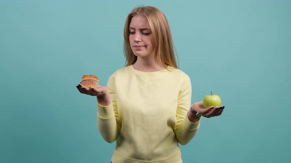 Young Woman Choosing Between Apple and Cupcake, the Girl Is Choose Cupcake