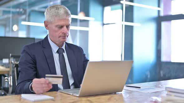 Middle Aged Businessman Using Credit Card on Laptop