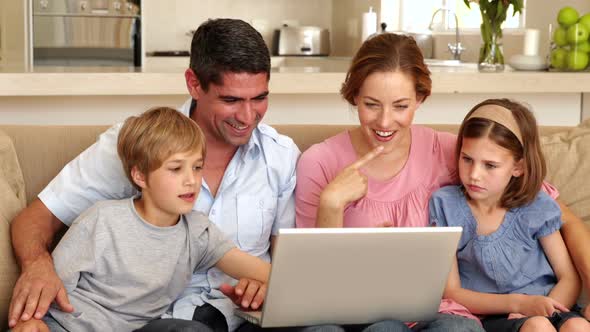 Happy family sitting on the sofa using laptop