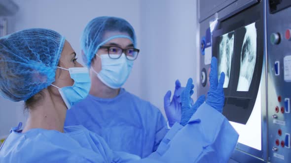 Diverse male and female surgeons wearing surgical caps and face masks discussing x ray