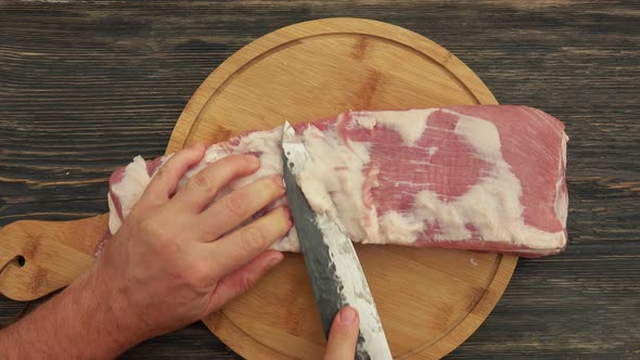 Top View of the Hands Cutting Off the Fat From the Ribs on a Background of Table