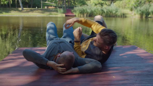 Loving Homosexual Partners Lying on Pier By Pond