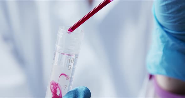 Scientist with Pipette Analyzes Red Colored Liquid To Extract the DNA