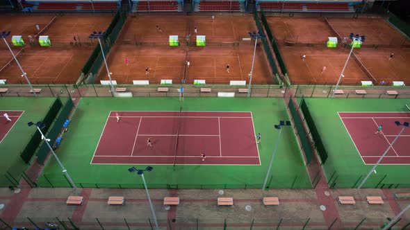 Aerial view of the sports club with many dirt tennis courts in the evening.