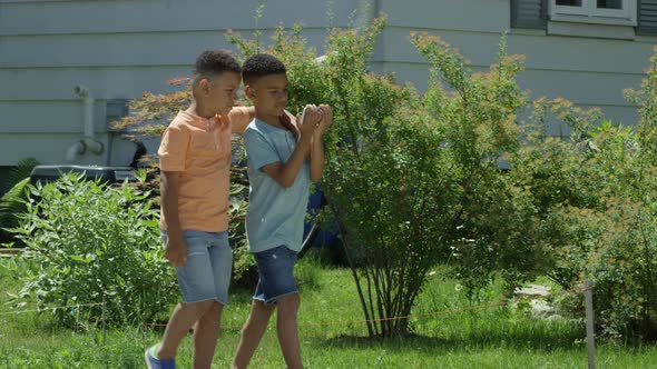 Two brothers walking down street watching video on smart phone