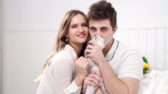 A Beautiful Couple of Young Lovers Holding a Small White Kitten