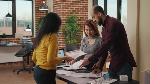 Diverse Team of Coworkers Analyzing Business Charts on Files