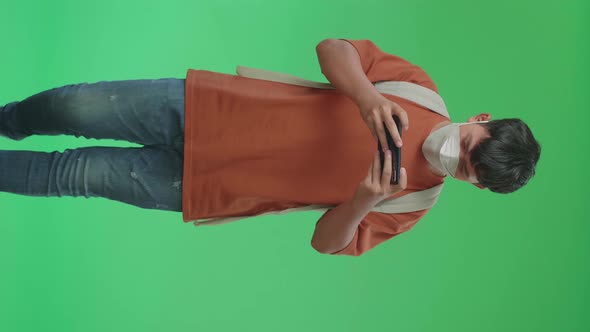 Asian Boy Student Wearing A Mask, Playing Game On Mobile Phone While Walking On Green Screen