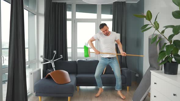 Man Does the Cleaning and Imagines Himself a Rock Star Plays the Broom Like a Guitar