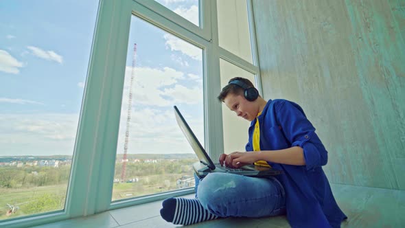 Happy boy in headphones with a laptop at home