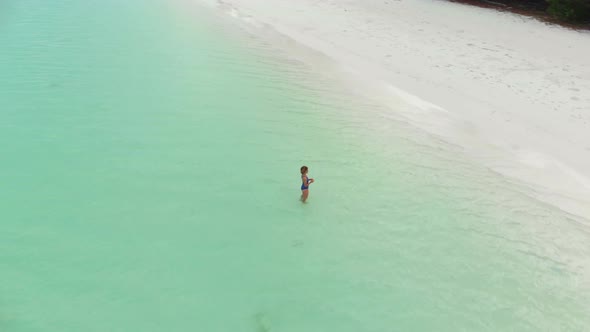 Aerial: Woman relaxing in turquoise water white sand beach tropical coastline Pa