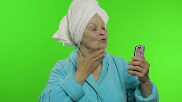 Elderly Grandmother in Bathrobe. Old Woman Using Mobile Phone for Video Call