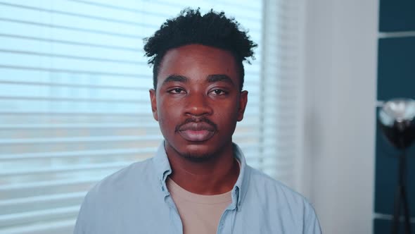 Young African American Man Office Worker Looking at Camera Stands Near Window