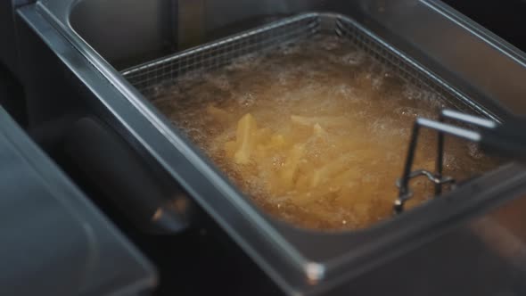 French Fries Fried in a Wire Basket in Hot Oil