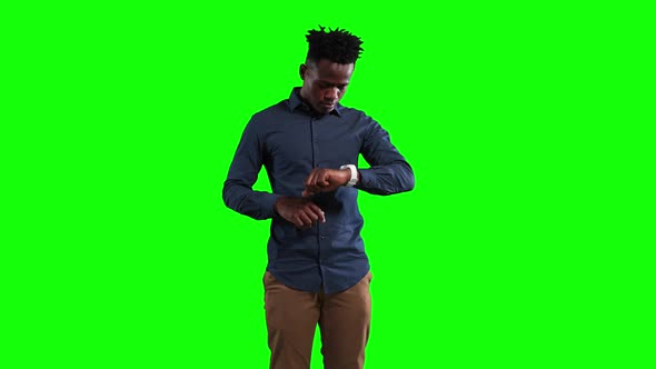 an African American man checking his smartwatch in a green background