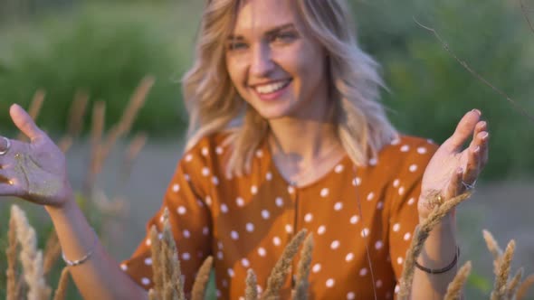 Attractive Young Woman Hands with Golden Glitters in the Field on Sunset