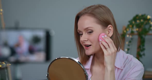 Woman Talking and Using Cosmetic Sponge While Sitting in Front of Mirror and Recording Video for Her