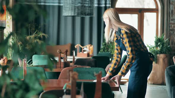 Restaurant Waitress is Cleaning Tables in a Face Mask