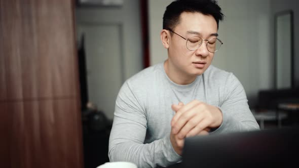 Asian confident man wearing eyeglasses talking by video call on laptop