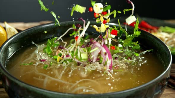 Super Slow Motion Detail Shot of Ingredients Falling Into Vegetable Pho Soup at 1000 Fps.