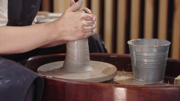 Hands of Elderly Woman Pulls Up and Down a Piece of Wet Clay on the Pottery Wheel