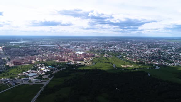 Aerial hyperlapse of green meadow, forest and city in summer day. Drone footage