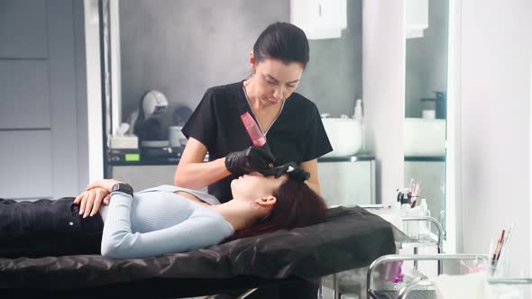 Master Makes Permanent Eyebrow Makeup Procedure to Woman in Beauty Salon