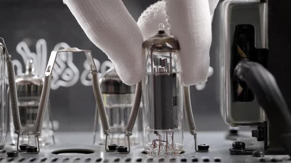 An Engineer in a Repair Shop Is Replacing Old Radio Tubes. The Hand Removes the Vacuum Tube From the