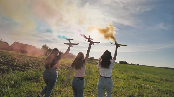 Happy Friendly Friends are Running with Toy Planes That Emit Colored Smoke