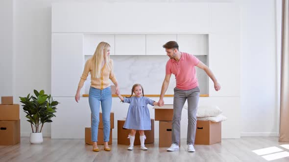 Happy family parents and preschooler daughter new apartment owners jump