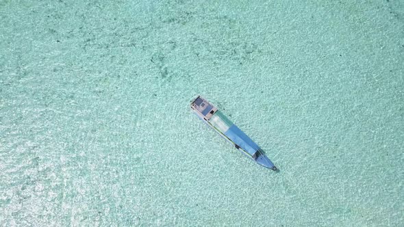 Aerial drone bird's eye view video of a traditional boat in the middle of turquoise and clean water.