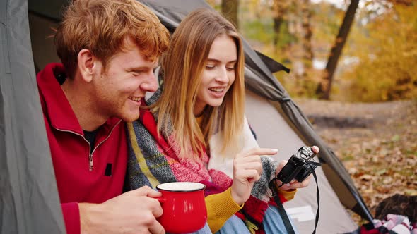 Young Man and Woman Smiling Talking Looking at Camera and Discussing Photos