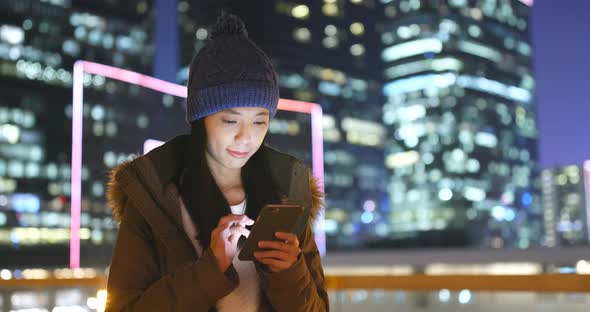 Woman Use of Smart Phone in The City at Night, Urban Cityscape Background of Hong Kong