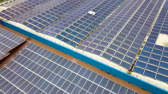 Aerial view of solar power plant with blue photovoltaic panels mounted of industrial building roof.