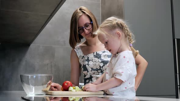 Young Mom with Little Daughter Cooking Dinner