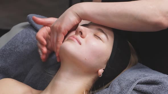 Young Woman Receives Facial Muscle Relaxation and Buccal Massage in a Luxury Beauty Salon