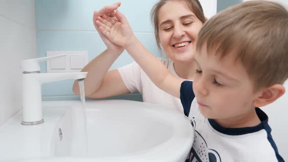 Portrait of Smiling Little Boy with Mother Washing and Cleaning Dirty Mouth with Water in the