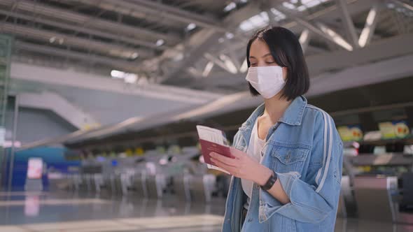 Woman passenger wearing face mask walking in airport terminal to boarding gate during pandemic.