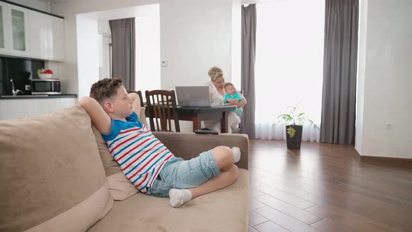 Cute Boy Relaxing on Couch While Mother Playing with Toddler