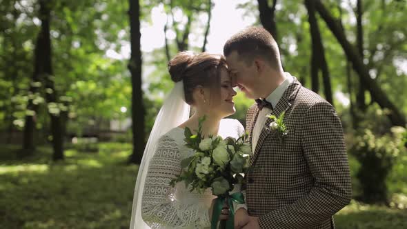 Newlyweds. Caucasian Groom with Bride Walking, Embracing, Hugs in Park. Wedding Couple