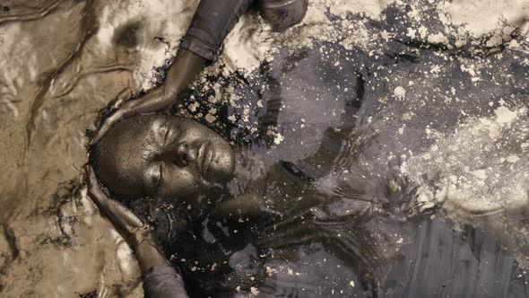 A Woman Dives Into the Water Lying on Her Back Covered All Over with Gold Paint