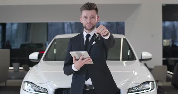 Portrait of Handsome Caucasian Male Trader with Tablet Showing Car Keys To Camera. Confident Young