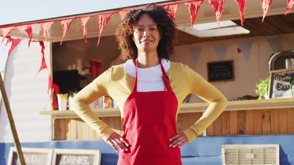 Portrait of african american woman with arms on hips smiling while standing near the food truck