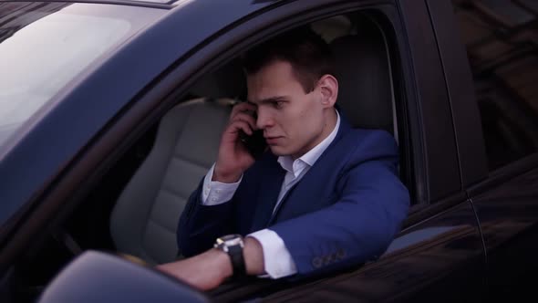 Handsome Man Sitting in the Car on a Driver's Seat Holding Hand on the Car Door