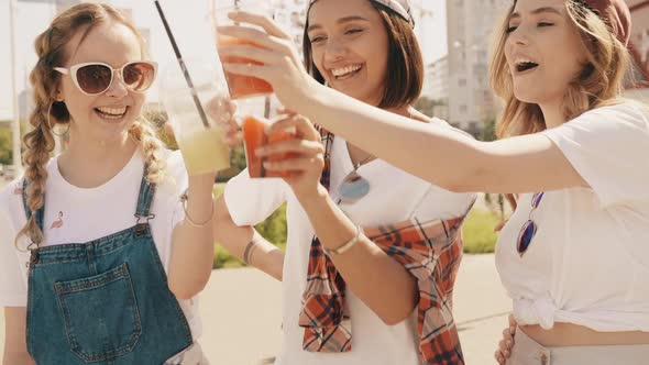 Positive models holding and drinking fresh cocktail smoothie outdoors