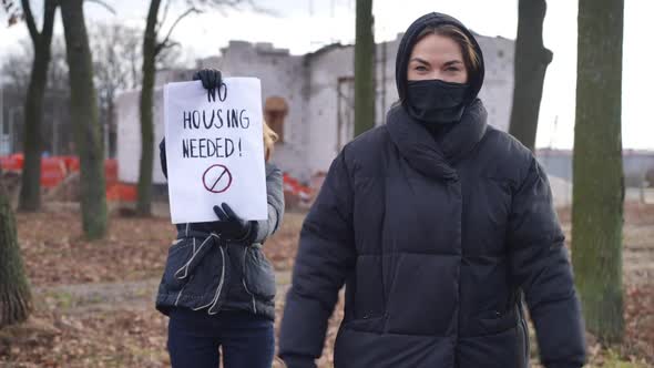 Young Caucasian Woman in Covid Face Mask Gesturing Thumbs Down As Friend Showing No Housing Needed