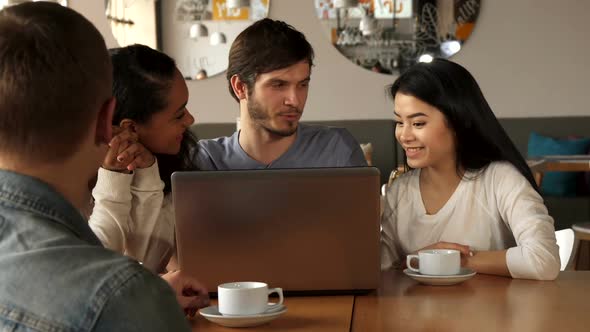 Friends Watch Something on Laptop at the Cafe